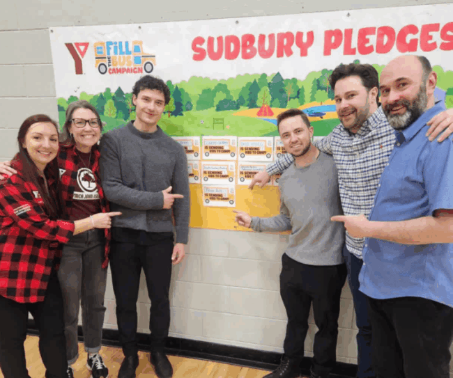 Team King members standing beside the YMCA Fill the Bus Sudbury pledge board after raising $4,100 to send 15 kids to John Island Camp in 2026.